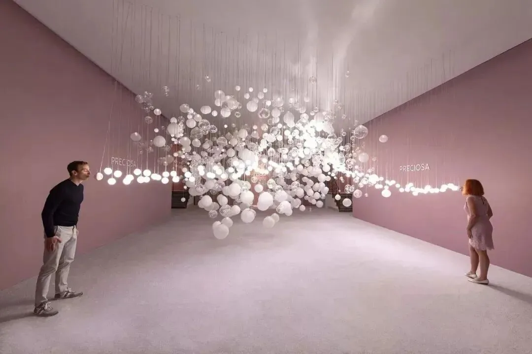 粉色展厅中悬挂着成片的白色水晶灯球,两位观众站在两侧